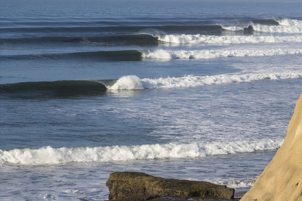 Lines of waves rolling toward a rocky point