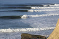 Lines of waves rolling toward a rocky point