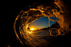 A wave curling around the setting sun