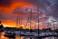 Sailboat masts in a harbor under a red and orange sunset sky