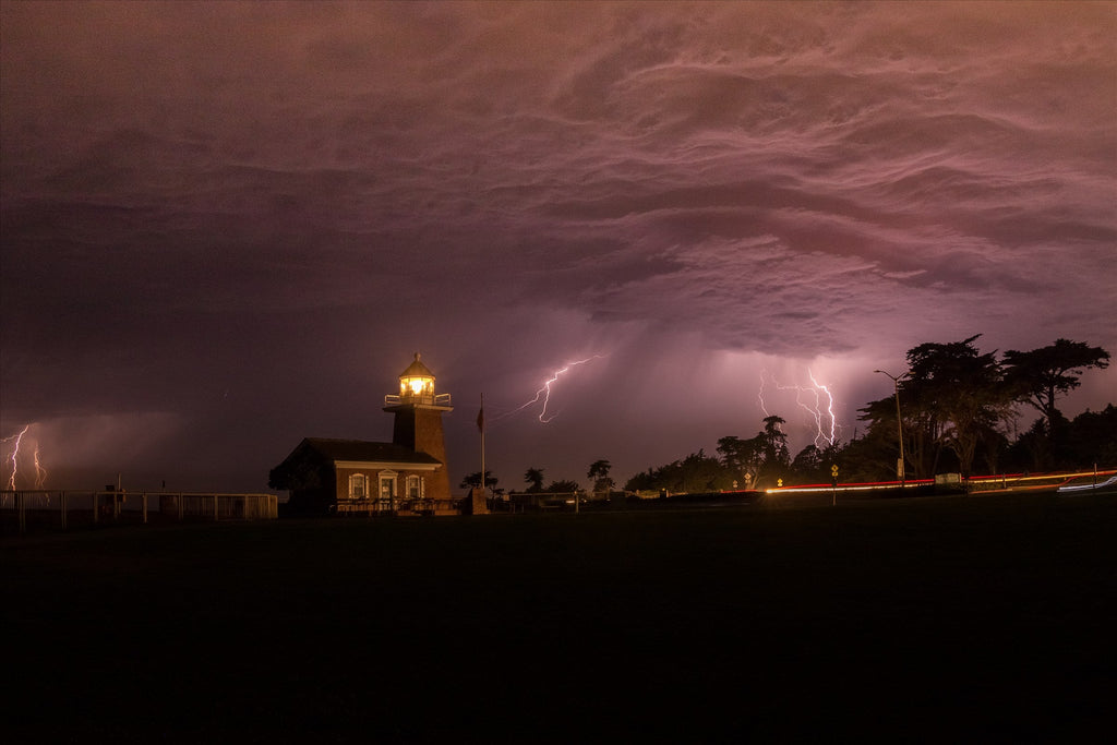 Lightning behind a lighthouse under a stormy purple sky