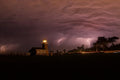 Lightning behind a lighthouse under a stormy purple sky