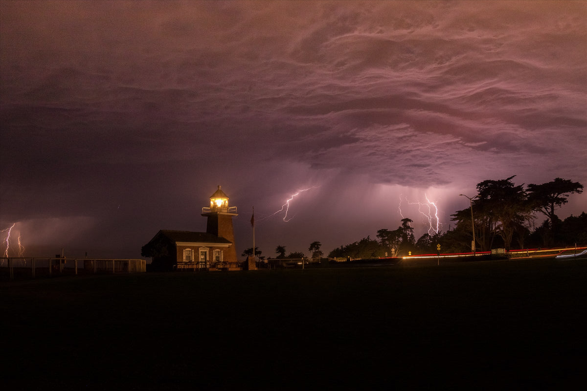 Lightning behind a lighthouse under a stormy purple sky