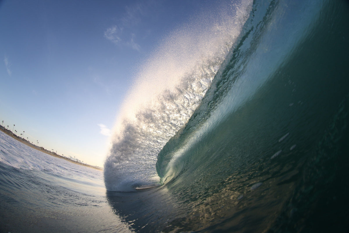 A steep blue wave face lit from behind with a curved horizon line
