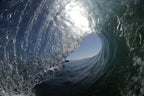 The inside of a glassy wave with a bright blue opening and silver textured water