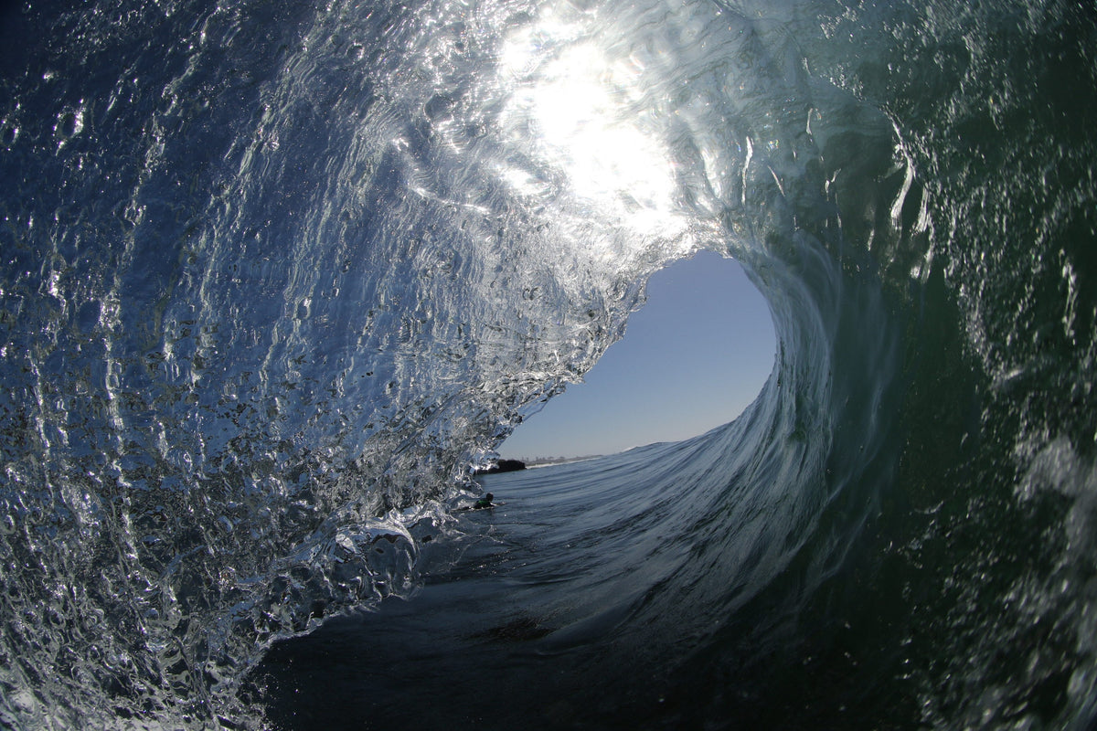 The inside of a glassy wave with a bright blue opening and silver textured water