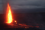 A fountain of lava shooting up from a dark crater under a stormy sky