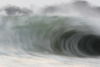 A huge curling wave seen close with soft grey and green tones