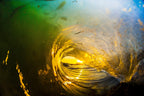 Inside a glowing golden wave barrel seen from underwater