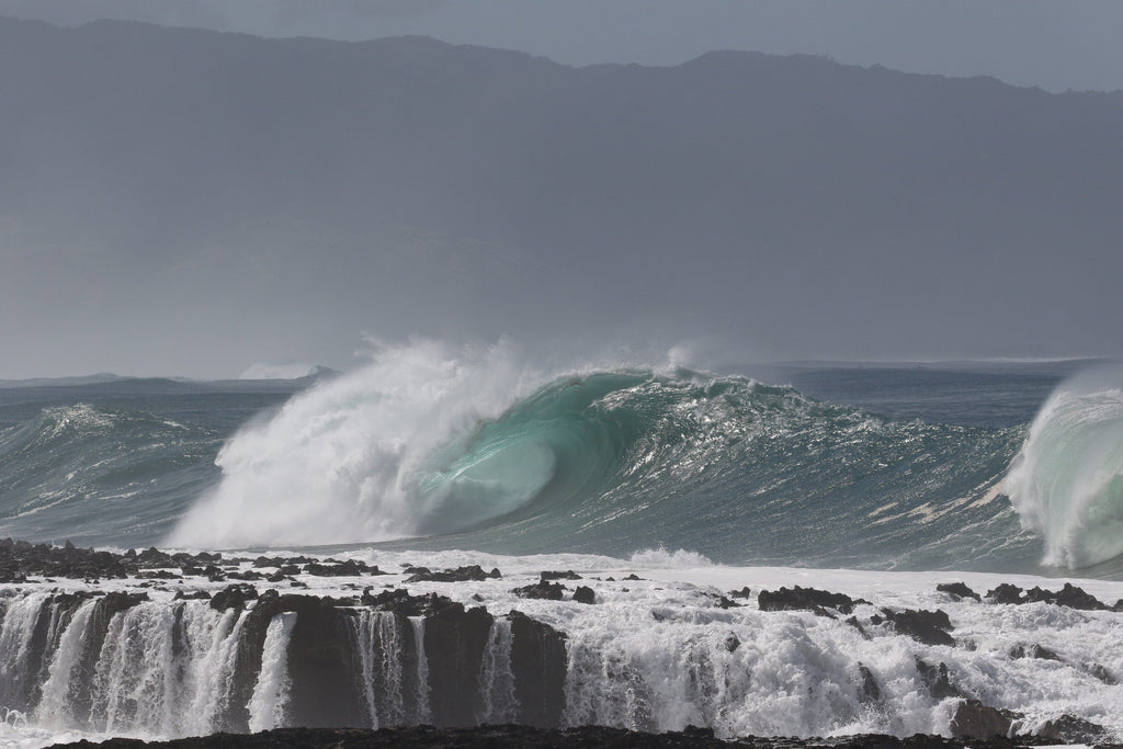 A wave peeling over a stepped reef ledge with white water pouring off it