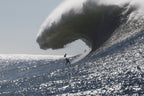 A massive wave curling over a sparkling silver ocean