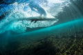An underwater view of a wave breaking over a surfer on a board