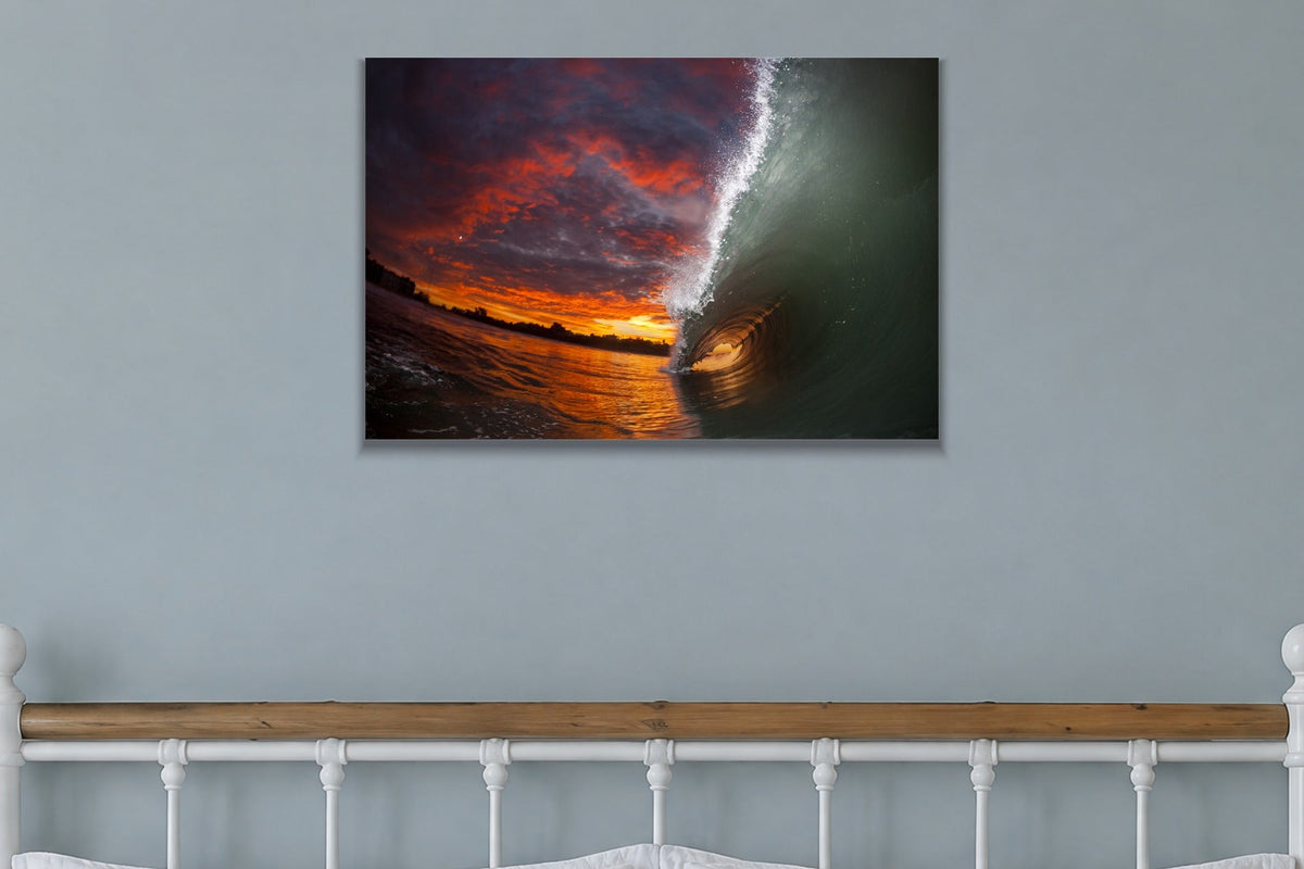 A tunnel of water lit by a fiery orange and red sunset sky shown large on the wall of a lived-in room
