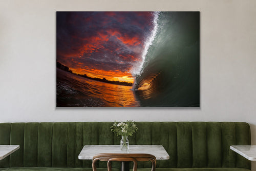 A tunnel of water lit by a fiery orange and red sunset sky shown large on the wall of a lived-in room