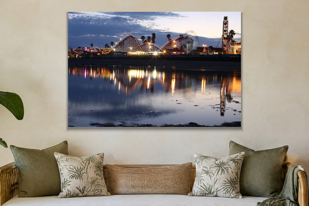A seaside amusement park with a roller coaster and Ferris wheel reflected in still water at dusk shown large on the wall of a lived-in room