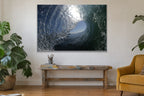 The inside of a glassy wave with a bright blue opening and silver textured water shown large on the wall of a lived-in room