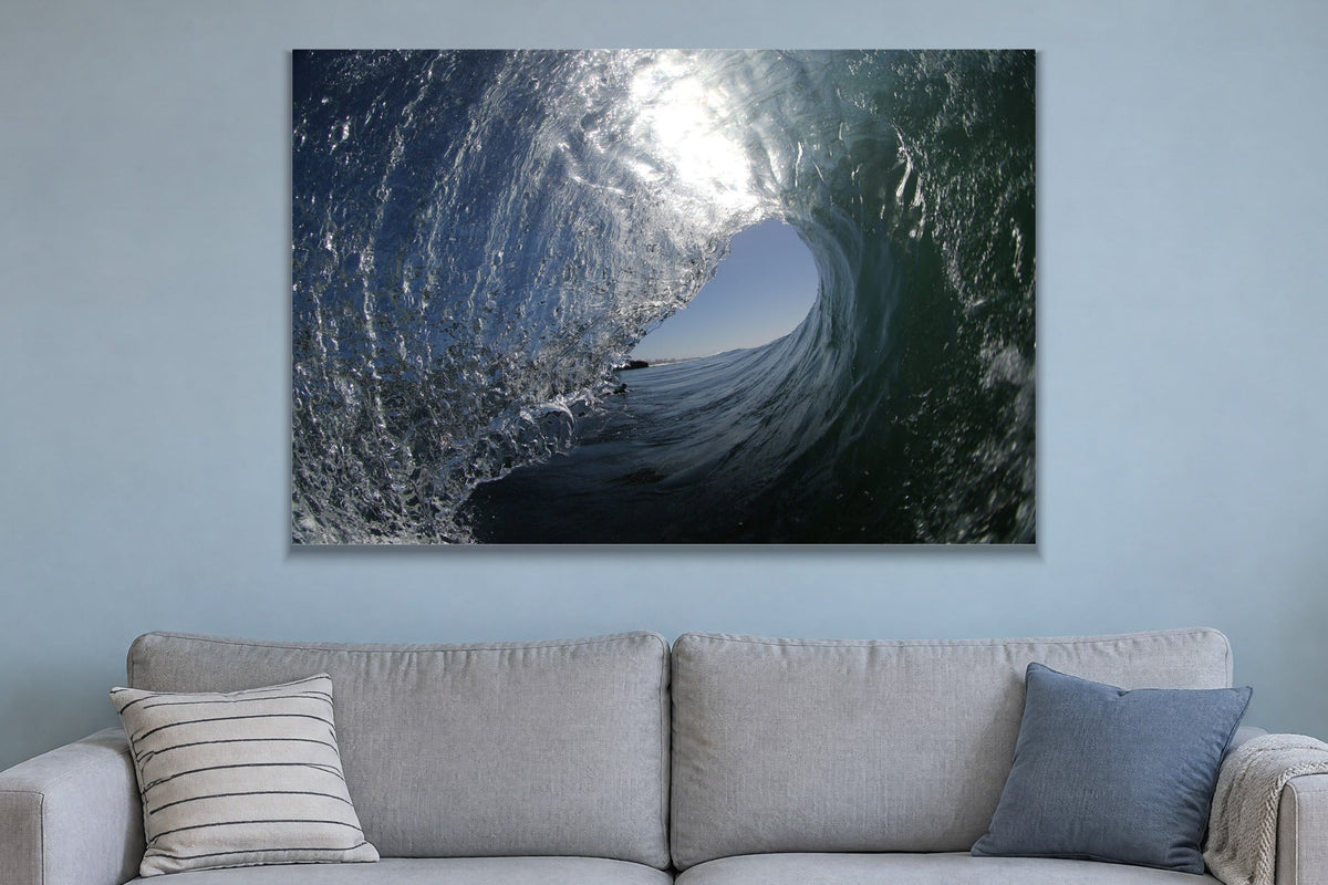 The inside of a glassy wave with a bright blue opening and silver textured water shown large on the wall of a lived-in room