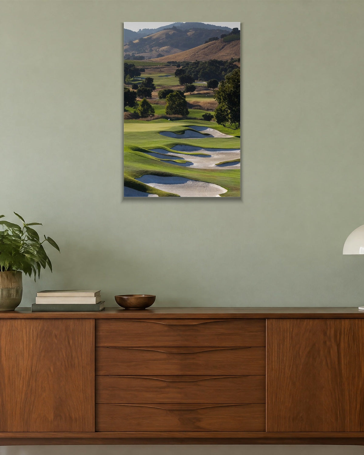 A golf course fairway winding through green hills with white sand bunkers shown large on the wall of a lived-in room
