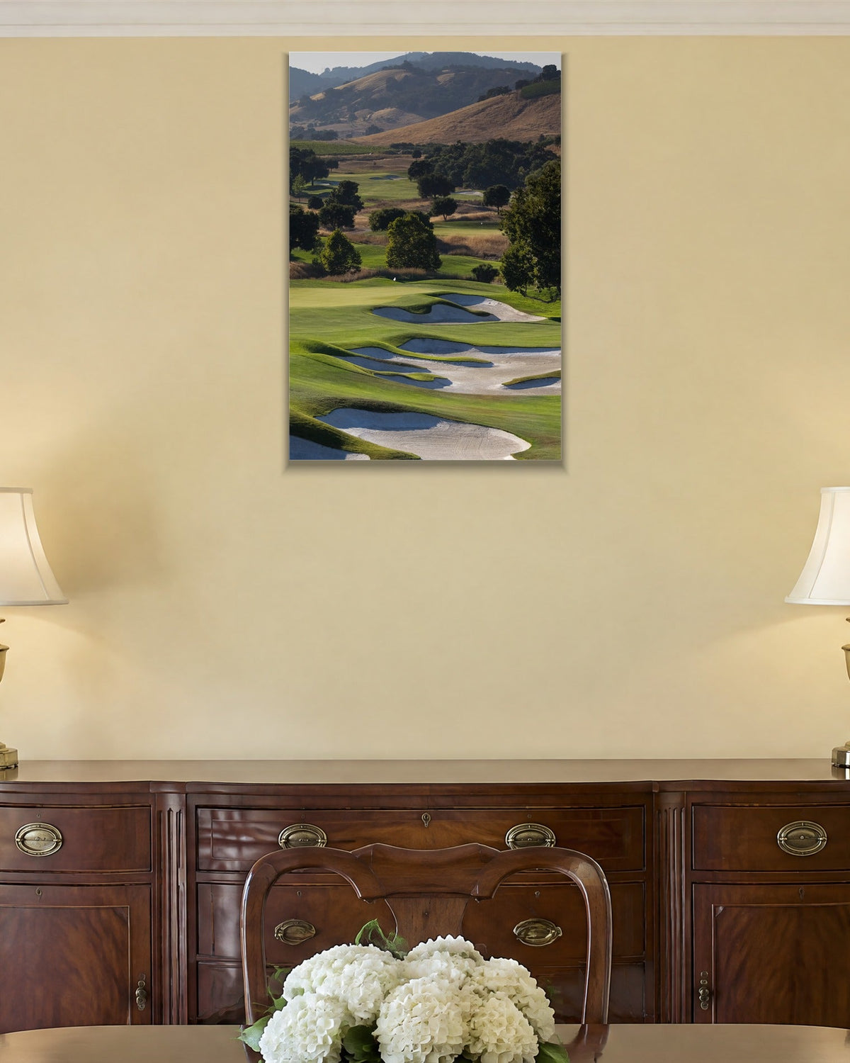 A golf course fairway winding through green hills with white sand bunkers shown large on the wall of a lived-in room