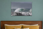 A wave peeling over a stepped reef ledge with white water pouring off it shown large on the wall of a lived-in room