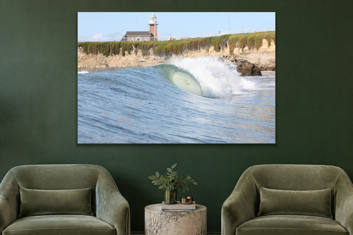 A glassy wave breaking along a cliff below a brick lighthouse shown large on the wall of a lived-in room
