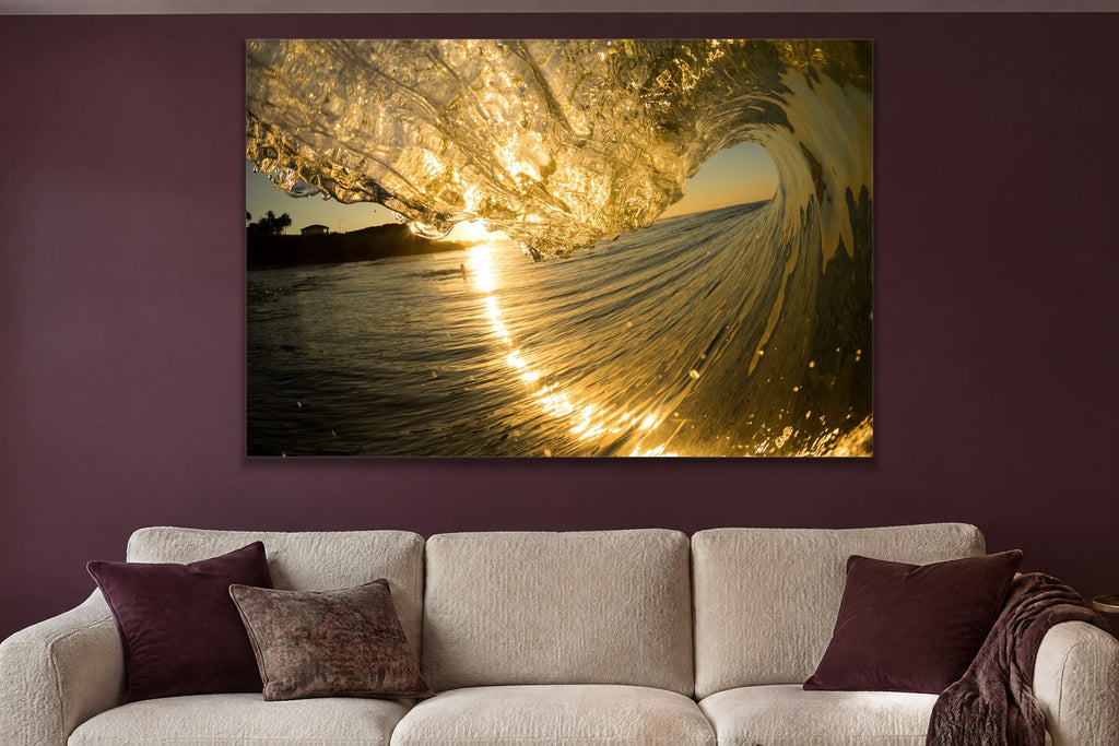 A wave curling in gold light with glittering water streaming down its face shown large on the wall of a lived-in room