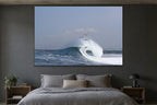 Three pelicans gliding above a wave as it curls and breaks shown large on the wall of a lived-in room