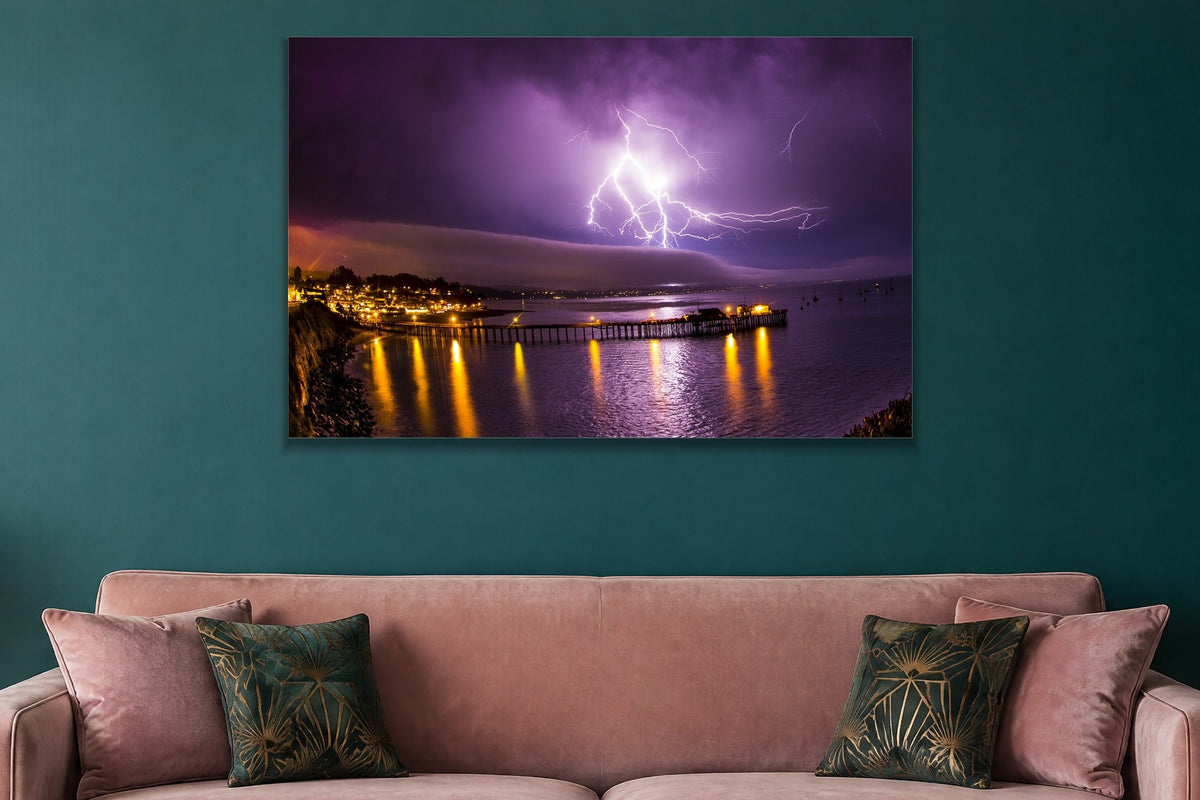 Lightning Over the Pier metal print hanging above furniture in a living space