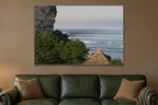 Long lines of swell marching past a rocky headland with a stone pyramid shown large on the wall of a lived-in room