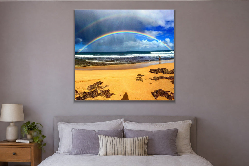 A rainbow over a gold sand beach with a lone person at the waterline shown large on the wall of a lived-in room