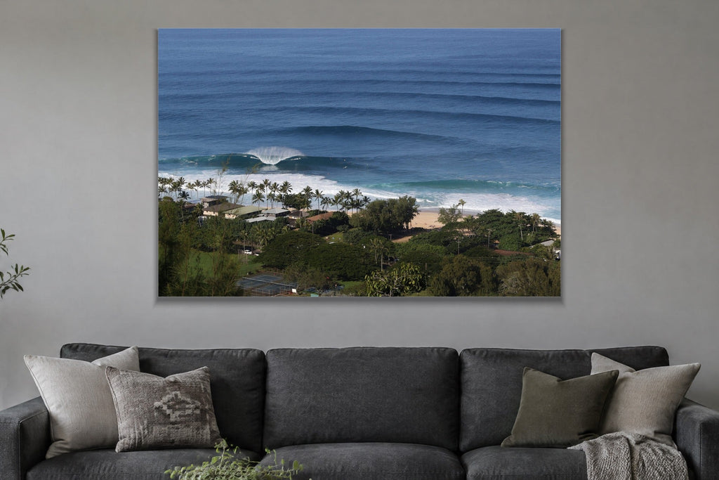 Long lines of swell approaching a palm-lined beach from above shown large on the wall of a lived-in room