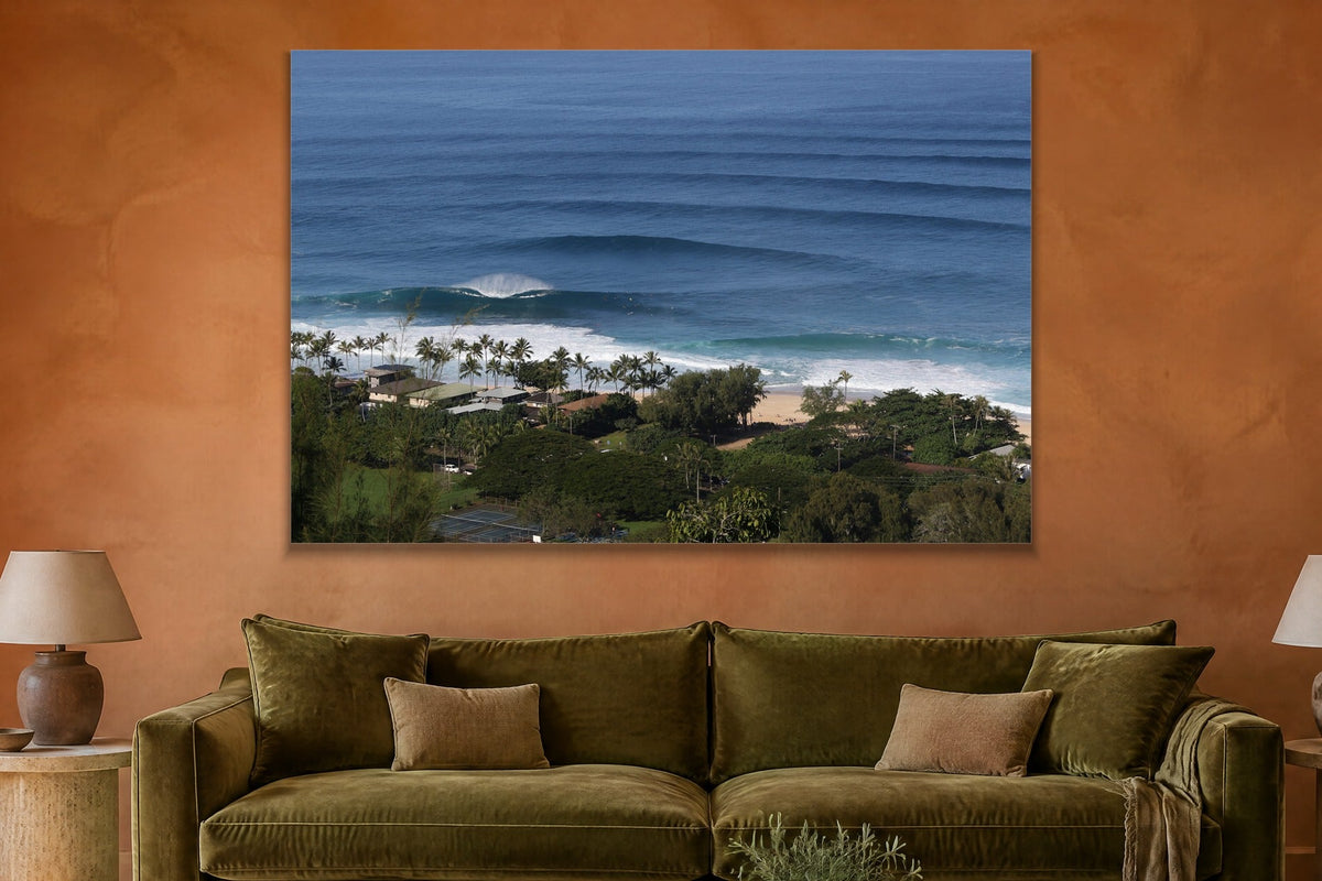 Lines of blue swell approaching a tropical shore with palm trees and houses shown large on the wall of a lived-in room