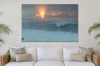 A glowing sun behind clouds above a peeling blue wave shown large on the wall of a lived-in room