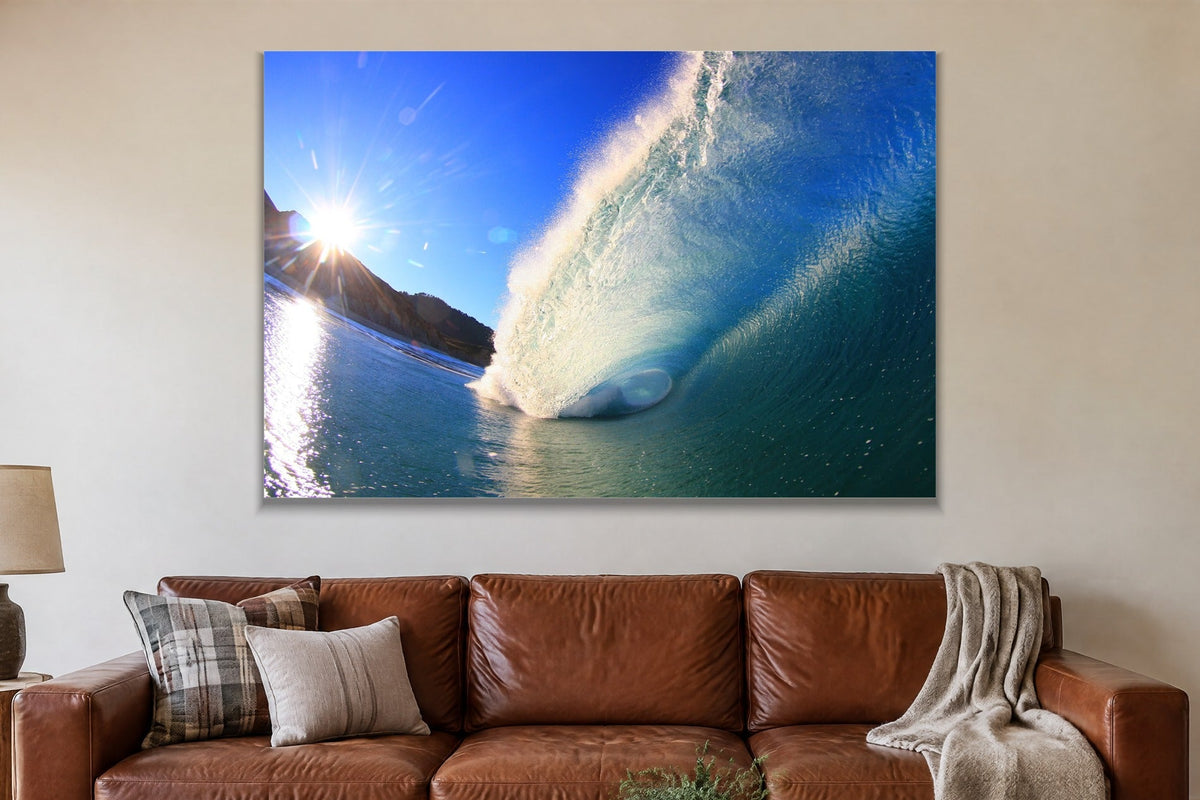 A bright blue wave lit by a sunburst over a rocky point shown large on the wall of a lived-in room