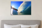 A bright blue wave lit by a sunburst over a rocky point shown large on the wall of a lived-in room
