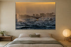 A whale fluke rising above dark water at golden hour with a second whale beside it shown large on the wall of a lived-in room